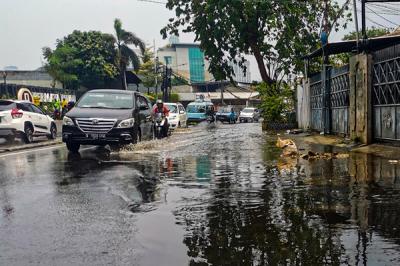Kendaraan saat melintasi genangan air di jalan raya Kebayoran Lama, Jakarta Selatan, Minggu (19/9/2021).