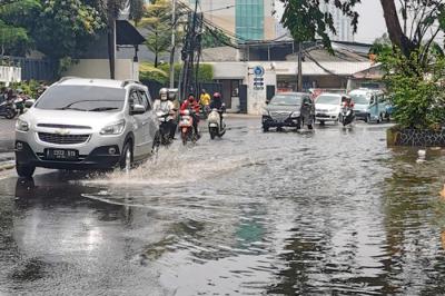 Kendaraan saat melintasi genangan air di jalan raya Kebayoran Lama, Jakarta Selatan, Minggu (19/9/2021).