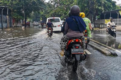 Kendaraan saat melintasi genangan air di jalan raya Kebayoran Lama, Jakarta Selatan, Minggu (19/9/2021).