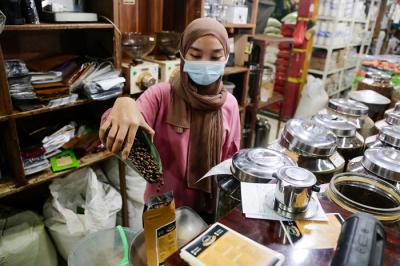 Suradi (42) pemilik Toko Dunia Kopi berpose di kiosnya di Pasar Santa, Jakarta Selatan, Senin (20/9/2021).