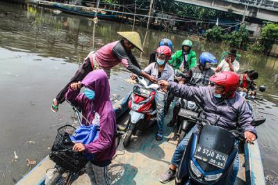 Sejumlah pengendara motor menggunakan jasa perahu eretan di kawasan Kali Angke, Kapuk, Jakarta Barat, Senin (20/9/2021).