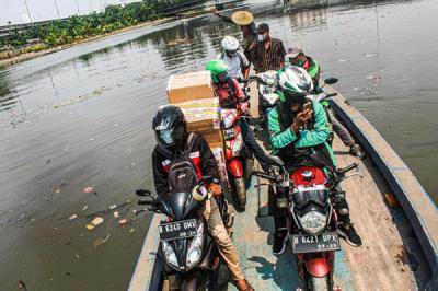 Sejumlah pengendara motor menggunakan jasa perahu eretan di kawasan Kali Angke, Kapuk, Jakarta Barat, Senin (20/9/2021).