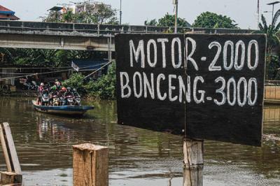 Sejumlah pengendara motor menggunakan jasa perahu eretan di kawasan Kali Angke, Kapuk, Jakarta Barat, Senin (20/9/2021).