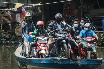 Sejumlah pengendara motor menggunakan jasa perahu eretan di kawasan Kali Angke, Kapuk, Jakarta Barat, Senin (20/9/2021).
