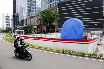 Warga melintas di dekat proyek pembangunan Tugu Sepeda di jalur pedestrian Jalan Jendral Sudirman, Jakarta Pusat, Kamis (23/9/2021).