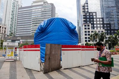 Warga melintas di dekat proyek pembangunan Tugu Sepeda di jalur pedestrian Jalan Jendral Sudirman, Jakarta Pusat, Kamis (23/9/2021).