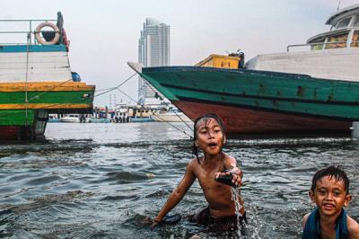 Sejumlah anak-anak sedang berenang riang di kawasan yang tergenang air laut di Dermaga Kali Adem, Jakarta Utara, Kamis (30/9/2021).
