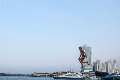 Sejumlah anak-anak sedang berenang riang di kawasan yang tergenang air laut di Dermaga Kali Adem, Jakarta Utara, Kamis (30/9/2021).