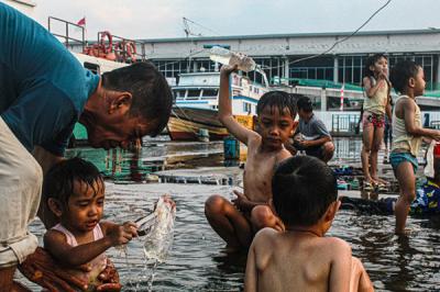 Sejumlah anak-anak sedang berenang riang di kawasan yang tergenang air laut di Dermaga Kali Adem, Jakarta Utara, Kamis (30/9/2021).