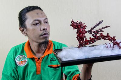 Seto Krisna Putra saat membuat miniatur robot dari limbah korek gas di Kantor Suku Dinas Lingkungan Hidup Jakarta Timur, Jumat (1/10/2021).