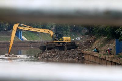 Petugas Dinas SDA Provinsi DKI Jakarta menggunakan alat berat saat mengeruk lumpur di aliran sungai Ciliwung, kampung Melayu, Jakarta, Senin (4/10/2021).