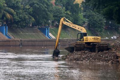 Petugas Dinas SDA Provinsi DKI Jakarta menggunakan alat berat saat mengeruk lumpur di aliran sungai Ciliwung, kampung Melayu, Jakarta, Senin (4/10/2021).