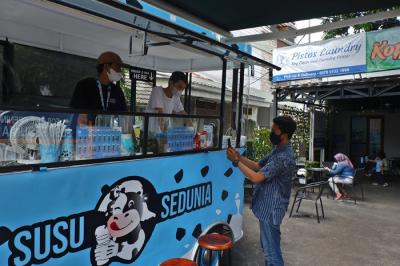Pembeli Susu Sedunia melakukan pembayaran secara digital atas gerobak UMKM di kawasan Bendungan Hilir, Jakarta Pusat, Minggu (3/10/2021).