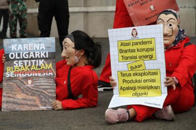 Sejumlah aktivis mengenakan kostum film Money Heist membentangkan poster saat melakukan aksi di depan Gedung DPR, Jakarta, Senin, (4/10/2021).