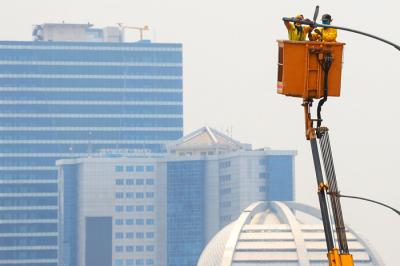 Petugas saat memperbaiki lampu penerangan di Jalan Gatot Subroto, Jakarta Selatan, Selasa (5/10/2021).
