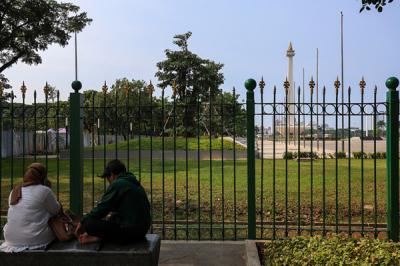 Pengunjung dan sejumlah petugas pengamanan saat berada di kawasan Monas, Jakarta Pusat, Kamis (7/10/2021).