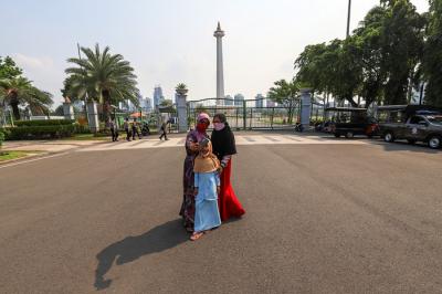 Pengunjung dan sejumlah petugas pengamanan saat berada di kawasan Monas, Jakarta Pusat, Kamis (7/10/2021).