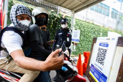 Pekerja melakukan pindai QR code melalui aplikasi PeduliLindungi di kawasan perkantoran Kebon Jeruk, Jakarta Barat, Jumat (8/10/2021).