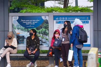 Para pekerja milenial saat menunggu transportasi umum di halte kawasan Sudirman, Jakarta, Jumat (8/10/2021).