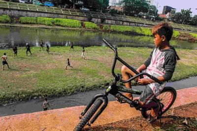 Sejumlah remaja memanfaatkan dataran sedimentasi lumpur kering untuk bermain sepak bola di kawasan Banjir Kanal Timur, Jakarta Timur, Rabu (13/10/2021).