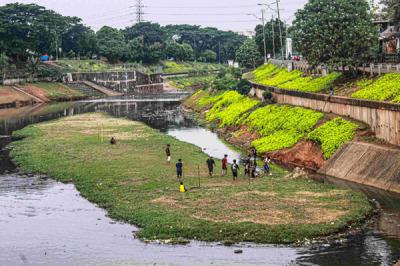 Sejumlah remaja memanfaatkan dataran sedimentasi lumpur kering untuk bermain sepak bola di kawasan Banjir Kanal Timur, Jakarta Timur, Rabu (13/10/2021).