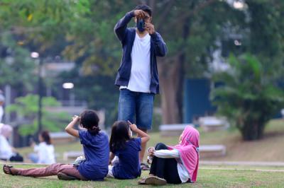 Warga menikmati suasana menjelang sore di Hutan Kota GBK Jakarta, Minggu (17/10/2021).