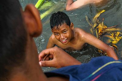 Anak-anak sedang bermain tanpa menggunakan masker di tepi sungai, Jakarta, Selasa (19/10/2021).