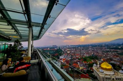 Pengunjung saat berfoto di atas gedung berlatar belakang pemandangan gunung dan awan di Bandung, Jawa Barat, Senin (25/10/2021).
