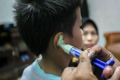 Relawan MNC Peduli memasangkan alat bantu dengar (ABD) untuk Fadli (9) yang mengalami gangguan pendengaran di Kebon Pala, Jakarta Timur, Jumat (29/10/2021).