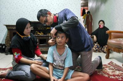Relawan MNC Peduli memasangkan alat bantu dengar (ABD) untuk Fadli (9) yang mengalami gangguan pendengaran di Kebon Pala, Jakarta Timur, Jumat (29/10/2021).