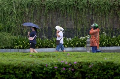 Warga berjalan sambil membawa payung saat hujan di kawasan Bundaran Hotel Indonesia, Jakarta, Senin (1/11/2021).