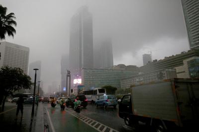 Warga berjalan sambil membawa payung saat hujan di kawasan Bundaran Hotel Indonesia, Jakarta, Senin (1/11/2021).