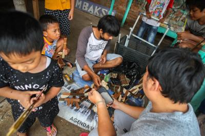 Aris (30) menyelesaikan kerajinan mainan dari limbah kayu di kawasam Pinang Ranti, Jakarta, Minggu (31/10/2021).
