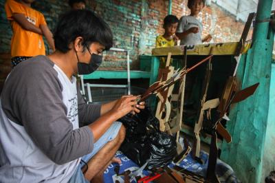 Aris (30) menyelesaikan kerajinan mainan dari limbah kayu di kawasam Pinang Ranti, Jakarta, Minggu (31/10/2021).