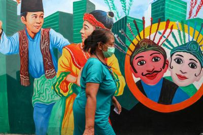 Warga melintas di gang bergambar mural dengan tema budaya Betawi di kawasan Kampung Sentra Kreatif di Kota Bambu Selatan, Jakarta Barat, Selasa (2/11/2021).