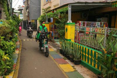 Warga melintas di gang bergambar mural dengan tema budaya Betawi di kawasan Kampung Sentra Kreatif di Kota Bambu Selatan, Jakarta Barat, Selasa (2/11/2021).