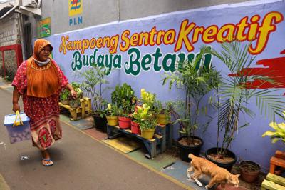 Warga melintas di gang bergambar mural dengan tema budaya Betawi di kawasan Kampung Sentra Kreatif di Kota Bambu Selatan, Jakarta Barat, Selasa (2/11/2021).