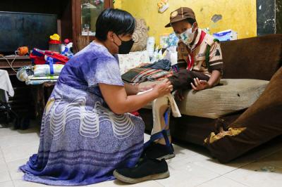 Rizki (9) dibantu ibunya Euis Paridah (40) saat mengenakan sepatu khusus di kediamannya di kawasan Menteng Dalam, Jakarta Selatan, Jumat (5/11/2021).