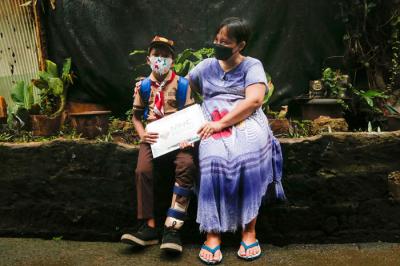 Rizki (9) dibantu ibunya Euis Paridah (40) saat mengenakan sepatu khusus di kediamannya di kawasan Menteng Dalam, Jakarta Selatan, Jumat (5/11/2021).