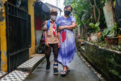 Rizki (9) dibantu ibunya Euis Paridah (40) saat mengenakan sepatu khusus di kediamannya di kawasan Menteng Dalam, Jakarta Selatan, Jumat (5/11/2021).