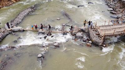 Foto udara saat warga melintasi sungai Ciberang melalui jembatan darurat yang putus akibat derasnya air sungai di Kampung Muhara, Kabupaten Lebak.