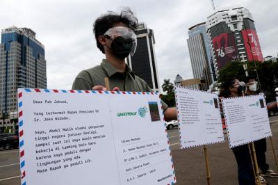 Relawan Greenpeace saat menggelar aksi 1.000 kartu pos rakyat untuk Presiden Joko Widodo di kawasan Patung Kuda, Jakarta Pusat, Rabu (10/11/2021).