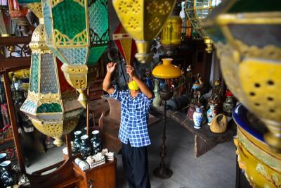 Andi (34) pedagang Lampion Antik membersihkan barang dagangannya di Kawasan Cilegon, Banten, Jumat (12/11/2021).