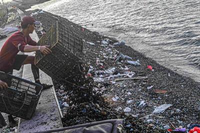 Warga membuang limbah kerang hijau di tepi laut Cilincing, Jakarta Utara, Selasa (16/11/2021).