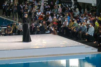 Model memperagakan busana muslim dalam acara Embracing Jakarta Muslim Fashion Week di Aquatic Center, Gelora Bung Karno, Senayan, Jakarta, Kamis (18/11/2021).