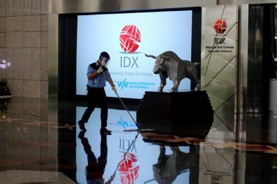 Karyawan membersihkan replika Patung Banteng Wulung didepan layar Indeks Harga Saham Gabungan (IHSG) di PT Bursa Efek Indonesia, Jakarta, Selasa (23/11/2021).