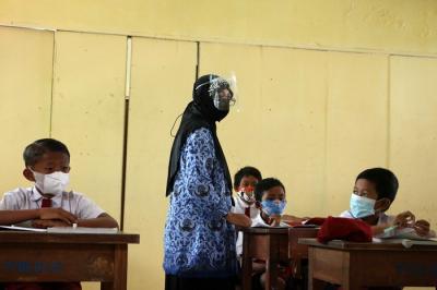 Tenaga pendidik Sekolah Dasar Negeri 01 Pagi Pulau Panggang Provinsi DKI Jakarta menggunakan seragam korpri dalam mengajar pertemuan tatap muka (PTM).