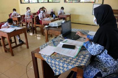 Tenaga pendidik Sekolah Dasar Negeri 01 Pagi Pulau Panggang Provinsi DKI Jakarta menggunakan seragam korpri dalam mengajar pertemuan tatap muka (PTM).