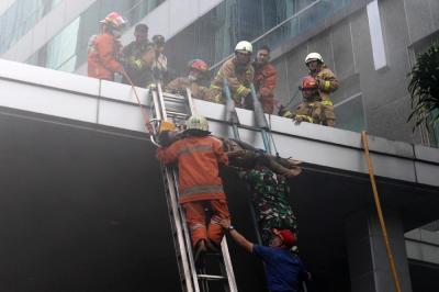 Petugas mengevakuasi korban kebakaran yang terjadi di Gedung Cyber 1, Jakarta, Kamis (2/12/2021).