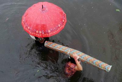 Sejumlah warga melewati banjir untuk mengungsi ketempat yang lebih aman di Makassar, Selasa (7/12/2021).